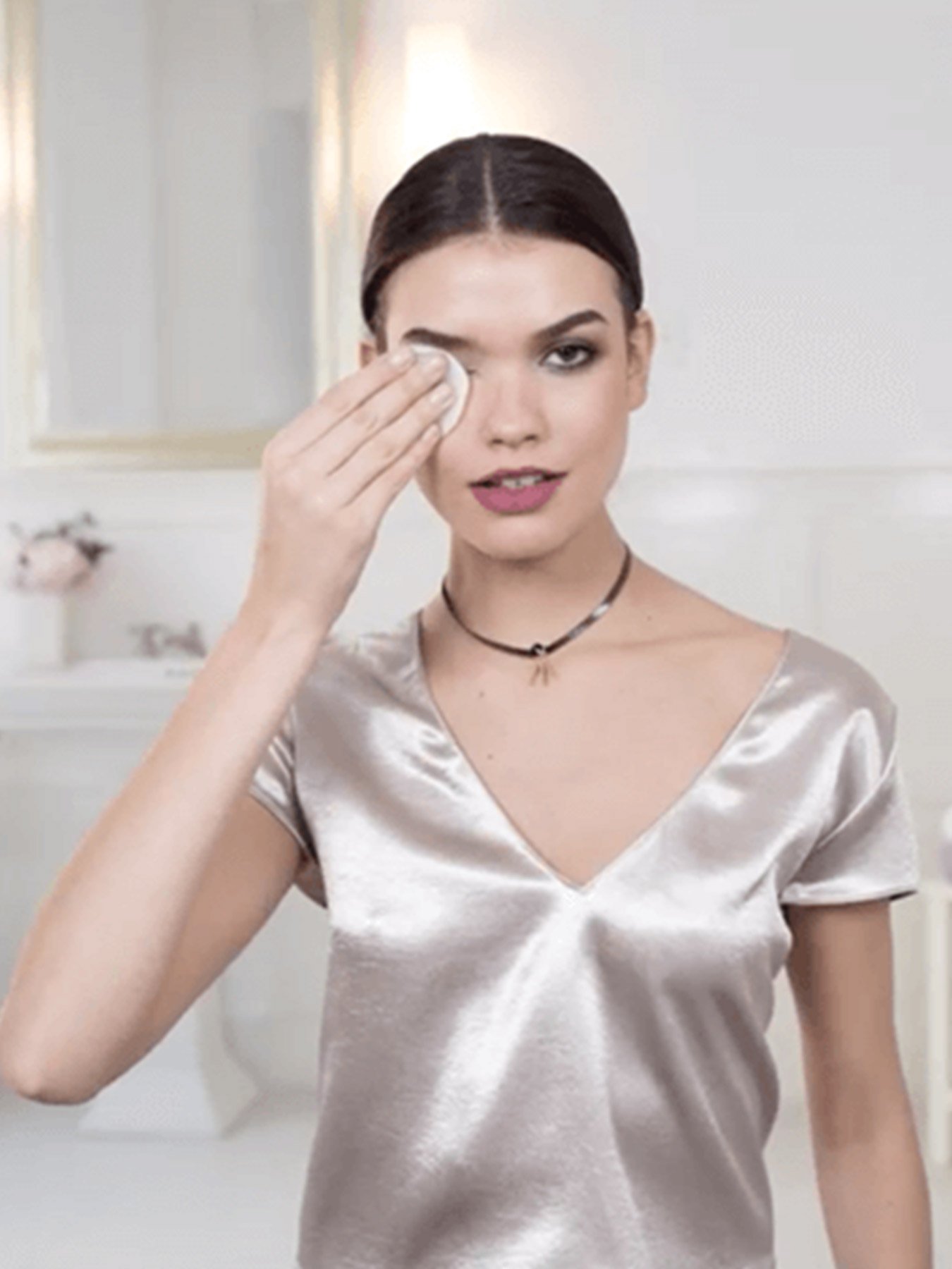 Woman with heavy makeup holds a Micellar Cleansing Water All-in-1 Waterproof pad over one eye.